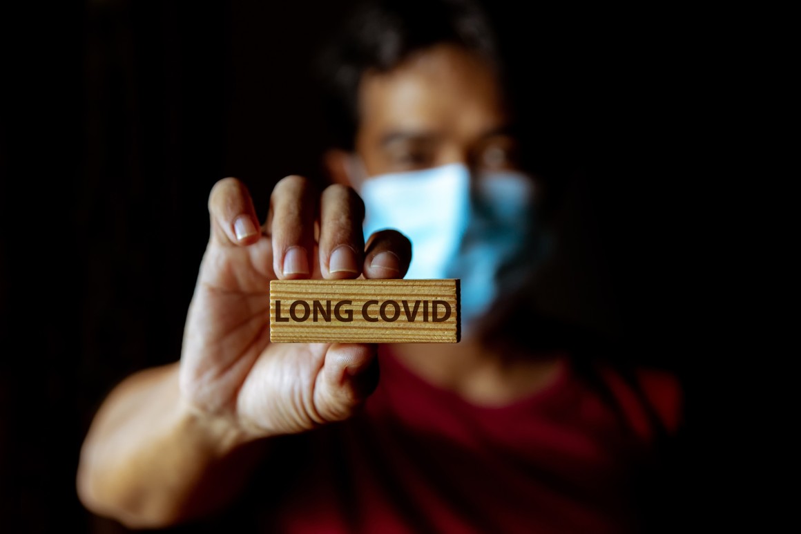 health worker holding long covid words